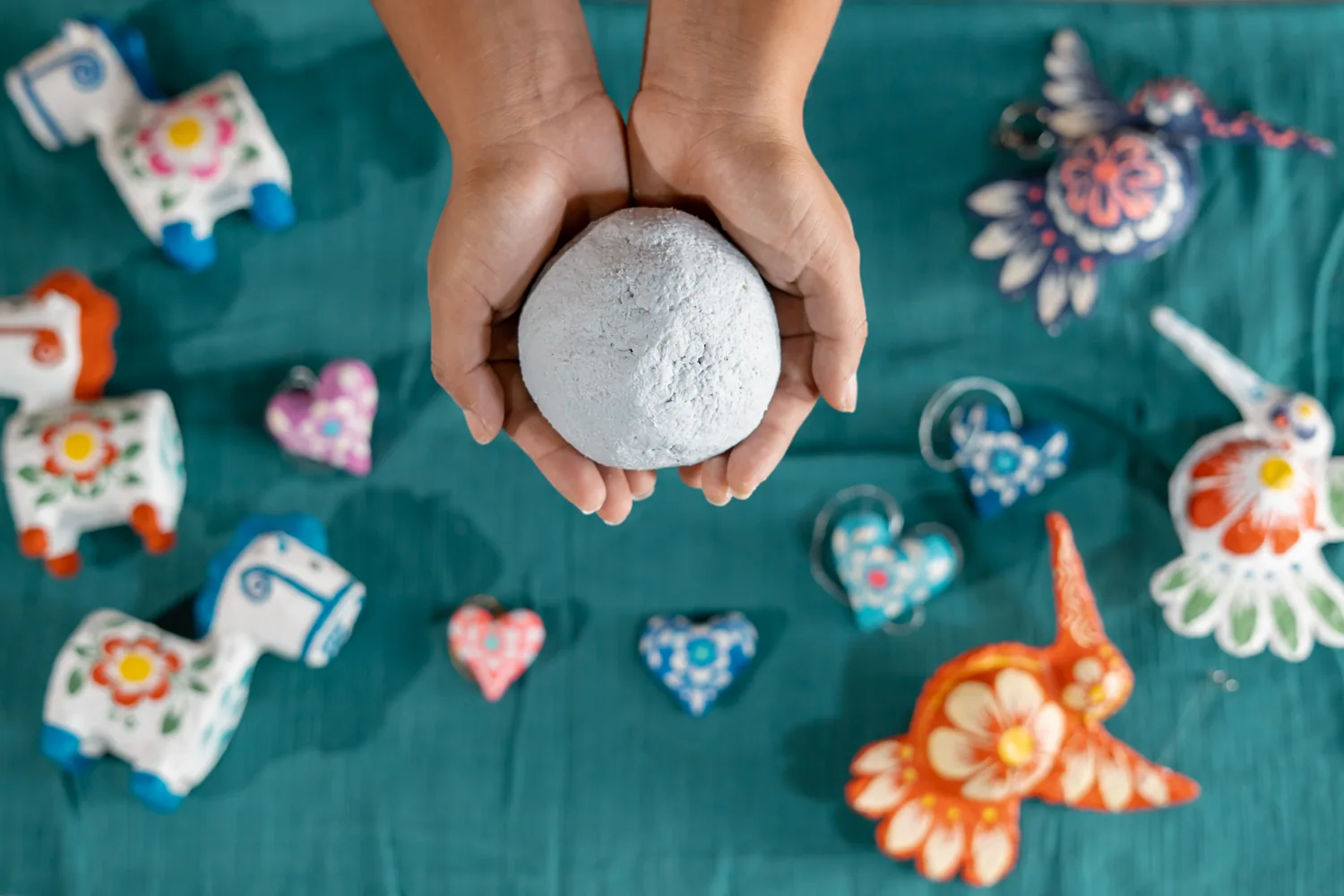 Piezas artesanales de colores y pequeños corazones sobre una mesa de trabajo